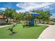 Community playground with colorful equipment, green turf, and trees on a sunny day at 4558 Baleno Ln, Kissimmee, FL 34746