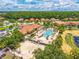 Aerial view of a community pool and sand volleyball court surrounded by lush greenery and colorful homes at 4558 Baleno Ln, Kissimmee, FL 34746