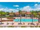 View of a community pool with palm trees and lounge chairs with people swimming on a sunny day at 4558 Baleno Ln, Kissimmee, FL 34746