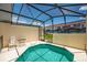 View of the screened-in pool and patio with view of the residences beyond the back fence at 4558 Baleno Ln, Kissimmee, FL 34746