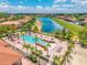 Aerial view of a pool surrounded by palm trees, lounge chairs and a sand volleyball court next to a lake at 4558 Baleno Ln, Kissimmee, FL 34746