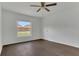 This bedroom features a window view, fresh white walls and complementary dark wood flooring at 4836 Pierce Arrow Dr, Apopka, FL 32712
