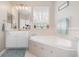 Serene bathroom with a large soaking tub, a window with sheer curtains, and neutral tiling for a spa-like ambiance at 538 Majestic Oak Dr, Apopka, FL 32712