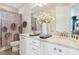 Bright bathroom featuring a double vanity with granite counters and a shower with decorative floral curtains at 7456 Marker Ave, Kissimmee, FL 34747
