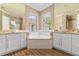 A primary bathroom with a soaking tub, dual sinks, granite counters, and white cabinetry is on display at 11333 Camden Park Dr, Windermere, FL 34786