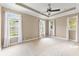 Neutral bedroom featuring three bright windows, a ceiling fan, and plush carpeting at 11333 Camden Park Dr, Windermere, FL 34786
