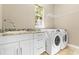 A modern laundry room with a sink, granite counters, white cabinets, and a new washer and dryer is pictured at 11333 Camden Park Dr, Windermere, FL 34786
