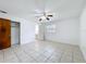 Spacious bedroom features tile floors, a ceiling fan, closet and a view to the en-suite bathroom at 1328 S Oxalis Ave, Orlando, FL 32807