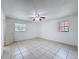 Well-lit bedroom featuring tiled floors, a ceiling fan, and two windows for natural light at 1328 S Oxalis Ave, Orlando, FL 32807