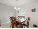 Inviting dining room with a wooden table, cushioned chairs, and a charming chandelier, bathed in natural light from the window at 141 Claire Ln, Davenport, FL 33837