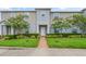 Charming two-story townhome with a well-maintained lawn, decorative shrubbery, and a brick path leading to the front door at 141 Claire Ln, Davenport, FL 33837