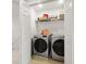 Bright laundry room with stainless steel washer and dryer, complemented by shelving for organized storage at 141 Claire Ln, Davenport, FL 33837
