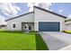 Charming single-Gathering home featuring a blue garage door, lush lawn, and modern architectural details at 16057 Sw 17Th Ave, Ocala, FL 34473