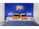 A cozy bedroom featuring a stylish blue accent wall, white nightstands, and lamps on either side of the bed at 2850 Bookmark Dr, Kissimmee, FL 34746