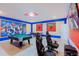 Bright game room with a pool table, gaming chairs, and superhero-themed decorations on the walls at 2850 Bookmark Dr, Kissimmee, FL 34746