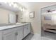 Double sink bathroom with neutral cabinets and tile; view into adjacent bedroom at 2907 Fable St, Kissimmee, FL 34746