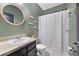 Bathroom featuring a vanity, commode, and shower with tub, all accented by soothing green walls at 311 Eaglecrest Dr, Haines City, FL 33844