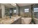 Bathroom with double sinks, granite countertops, a soaking tub, and a glass-enclosed shower at 316 Bennett St, Auburndale, FL 33823