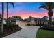 Stunning home exterior with a well-manicured lawn, mature palm trees, and a circular driveway at sunset at 3267 Regal Crest Dr, Longwood, FL 32779