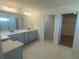 This bathroom features a double sink, vanity, and a doorway into a walk-in closet at 335 Ridgemark Ave, Groveland, FL 34736