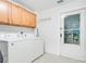 Bright laundry room with white appliances, wood cabinets, and access to the exterior at 378 Cedarbrook Ln, Altamonte Springs, FL 32714