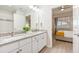 Bathroom with double vanity and a view into a bedroom with a plush bed and ceiling fan at 4001 Breakview Dr # D409, Orlando, FL 32819