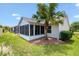 Cozy sunroom featuring large windows, lush green lawn, and a beautiful palm tree in the backyard at 449 Timmonsville Way, The Villages, FL 32162