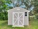 Exterior view of the shed in the backyard with white double doors and a window at 458 Spring Ln, Ocala, FL 34472