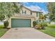 Charming two-story home featuring a large, green garage door, well-kept lawn, and beautiful, bright yellow exterior at 4901 Stone Acres Cir, St Cloud, FL 34771