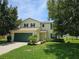 Two-story home with a well-manicured lawn, two-car garage, and dark green shutters at 4901 Stone Acres Cir, St Cloud, FL 34771