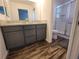 An updated bathroom with double vanity, gray cabinets, wood-look floors, and a glass shower enclosure at 744 Barron Pl, The Villages, FL 32163