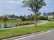 Serene community featuring a pond surrounded by lush landscaping and a walking path under a partly cloudy sky at 744 Barron Pl, The Villages, FL 32163
