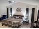 This is the main bedroom featuring a large bed, ceiling fan, and soft natural light from two windows at 744 Barron Pl, The Villages, FL 32163