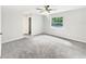 The spacious bedroom features plush gray carpet, a ceiling fan, and a bright window providing natural light at 1122 Romar Ln, Apopka, FL 32712