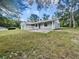 A charming single-story home is nestled among mature trees, featuring a covered porch and a serene setting at 1122 Romar Ln, Apopka, FL 32712
