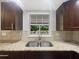 A well-lit kitchen sink area features granite counters, tile backsplash, and a bright window overlooking greenery at 1122 Romar Ln, Apopka, FL 32712