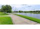 Paved walkway along the lake with lush, green grass and beautiful homes in the background on a sunny day at 11834 Gennaro Ln, Orlando, FL 32827