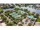 Aerial view of the tennis courts, pool and parking lot area surrounded by lush, green trees and a lake at 11834 Gennaro Ln, Orlando, FL 32827