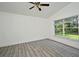 Bright, airy bedroom with new gray flooring, a ceiling fan, and a large window overlooking a green yard at 1502 W 16 Th Street, Sanford, FL 32771