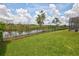 Well-maintained backyard with a pond view, enhanced by a black metal fence and vibrant green grass at 1528 Langham Ter, Lake Mary, FL 32746