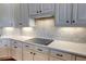 Close up of the kitchen featuring white cabinets, black hardware, backsplash, countertop, and stainless cooktop at 1528 Langham Ter, Lake Mary, FL 32746