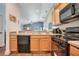 Open kitchen with wood cabinets, black appliances, and a view to the living area at 1531 Tiverton Blvd, Winter Garden, FL 34787