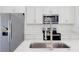 Close-up of a kitchen island with stainless steel sink, appliances, and white quartz countertops at 15625 Sw 37Th Cir, Ocala, FL 34473