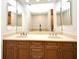 Bathroom featuring double vanity sinks with warm cabinets and a large mirror at 1649 Lake Baldwin Ln, Orlando, FL 32814