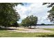 Sandy beach area with lake access, mature trees, and open green space at 1649 Lake Baldwin Ln, Orlando, FL 32814