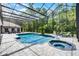 A screened-in pool and hot tub with brick pavers surrounded by lush greenery offers a private outdoor oasis at 1717 Fountainhead Dr, Lake Mary, FL 32746