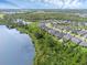 Aerial view of community featuring homes along a lake; a blend of natural beauty and residential living, surrounded by lush trees at 17860 Passionflower Cir, Clermont, FL 34714