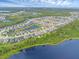 Wide aerial shot of a residential community, showcasing homes near a scenic lake and trees at 17860 Passionflower Cir, Clermont, FL 34714