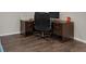 This home office space features wood-look flooring, a dark desk, and a black rolling chair at 17860 Passionflower Cir, Clermont, FL 34714