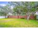 Large green backyard featuring a brick privacy wall and mature trees at 2031 Gloria Oak Ct, Orlando, FL 32820